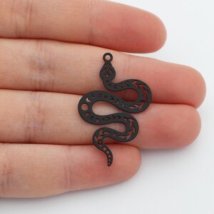Peut inclure: Breloque serpent en métal noir avec un design découpé détaillé.