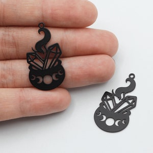 Puede incluir: Dos abalorios de metal negro con forma de caldero con tres lunas y cristales en su interior. Los abalorios tienen un diseño recortado y son perfectos para la elaboración de joyas.