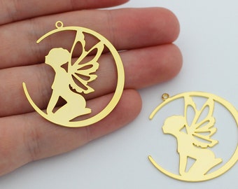 May include: Two gold-colored metal charms in the shape of a crescent moon with a fairy silhouette inside. The fairy is sitting with wings spread out.
