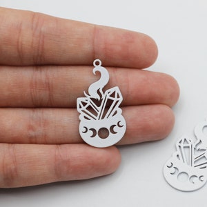 Puede incluir: Dos encantos de metal blanco con forma de caldero con cristales y un diseño de luna creciente.