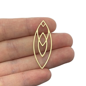 Op de afbeelding: Gouden metalen hanger met een geometrisch ontwerp. De hanger is ovaalvormig met een reeks overlappende vormen erin.