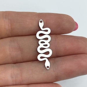 May include: A silver snake charm with a wavy design. The charm has a small hole at each end, likely for attaching to jewellery. The snake is depicted vertically, with a simple, stylized appearance.