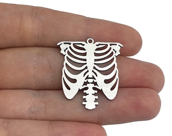 Puede incluir: Encanto de metal plateado en forma de caja torácica humana. El encanto está detallado con un diseño de caja torácica esquelética.