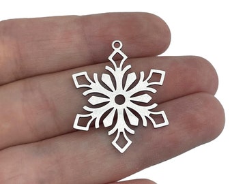 Op de afbeelding: Zilveren sneeuwvlok charme met een delicaat, ingewikkeld ontwerp. De charme is perfect om een ​​toets van winterse magie toe te voegen aan sieradenprojecten.