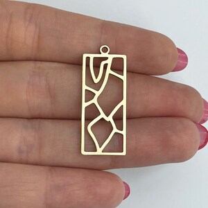 May include: Gold-toned metal pendant with a rectangular shape and a geometric pattern cut-out design.