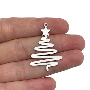 May include: Silver metal charm shaped like a Christmas tree with a star on top. The tree is made of a wavy line design.