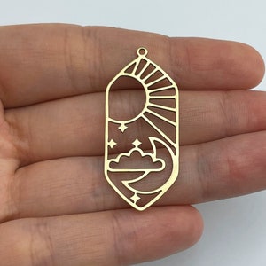 May include: Gold-toned metal charm with a sun and moon design. The charm is shaped like a teardrop and has a hole at the top for hanging.