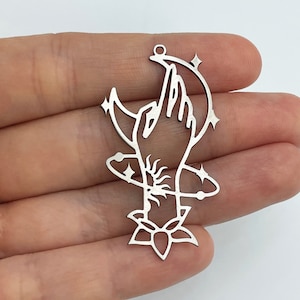 Peut inclure: Un pendentif argenté représentant une main tendue vers un croissant de lune, avec un soleil, des étoiles et un motif de fleur de lotus. Le pendentif a une petite boucle en haut pour l'accrocher.