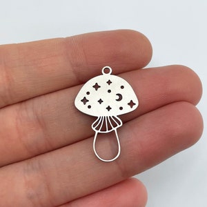 May include: A silver charm in the shape of a mushroom with a crescent moon and stars cut out of the top.