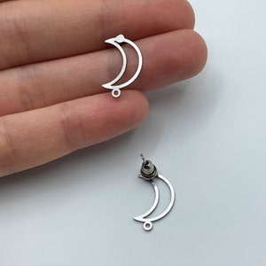 May include: Two silver crescent moon earring blanks with jump rings. The earring blanks are made of metal and have a smooth finish.
