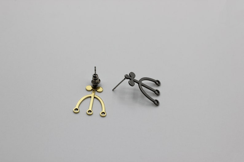 May include: A pair of earrings with a unique design. One earring is gold and the other is black.