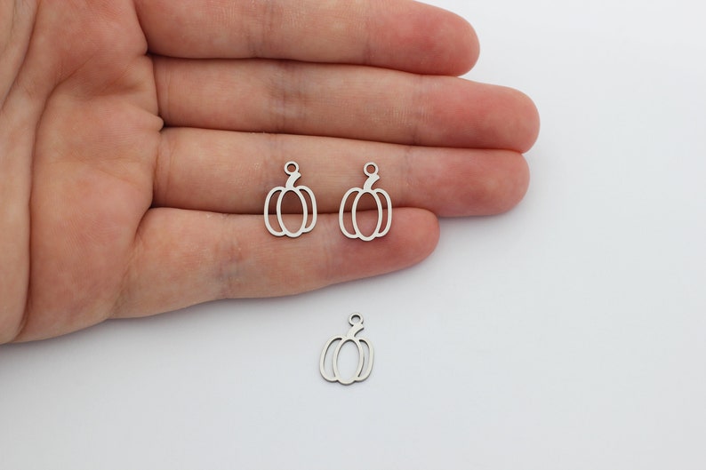 May include: Three silver metal pumpkin charms with a loop at the top for attaching to jewelry or other crafts.