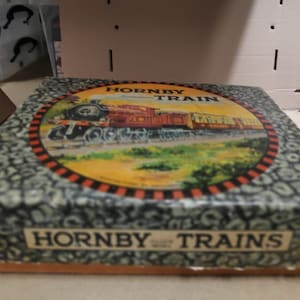 May include: Vintage Hornby Trains box featuring a colorful illustration of a steam train and passenger cars. The box has a patterned exterior and the words "HORNBY TRAIN" and "HORNBY TRAINS" are printed on the box.