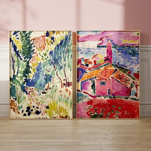 May include: Two framed abstract paintings with colourful brushstrokes. The painting on the left depicts a landscape with green and blue trees. The painting on the right shows a pink building with a red roof and a blue sea in the background.