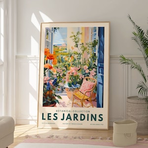 May include: A framed poster with a botanical illustration of a garden scene. The poster is titled "Les Jardins" and features a wicker chair with a pink cushion, a table with a potted plant, and a view of a garden with flowers and trees. The poster is in a white frame and is hanging on a white wall.