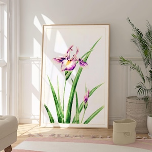 May include: A framed print of a watercolor painting of a purple and white iris flower with green leaves on a white background.