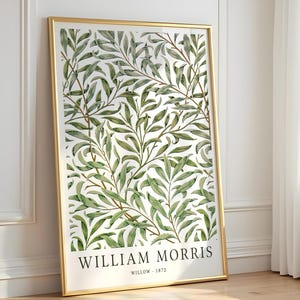 May include: A rectangular wall art print in a thin gold frame featuring a repeating botanical pattern of green willow leaves and brown stems. The bottom of the print displays the text WILLIAM MORRIS and the text WILLOW - 1872 in black font.