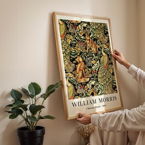Peut inclure: Une impression murale rectangulaire encadr&eacute;e pr&eacute;sentant le motif Charcoal Forest 1885 de William Morris. L'&oelig;uvre affiche un motif dense de feuillage vert, de paons et de renards sur fond noir, avec le texte William Morris Charcoal Forest 1885 imprim&eacute; en bas.