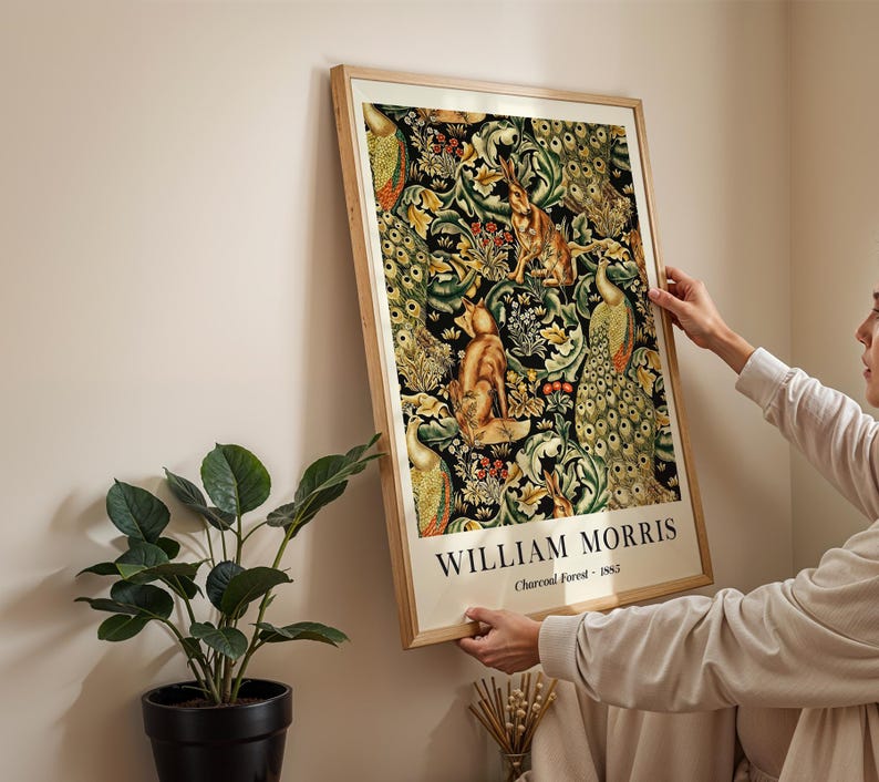 Peut inclure: Une impression murale rectangulaire encadr&eacute;e pr&eacute;sentant le motif Charcoal Forest 1885 de William Morris. L'&oelig;uvre affiche un motif dense de feuillage vert, de paons et de renards sur fond noir, avec le texte William Morris Charcoal Forest 1885 imprim&eacute; en bas.