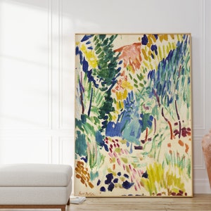 May include: Abstract painting of a landscape with vibrant colours, including green, blue, yellow, and pink. The painting is framed and hanging on a white wall.