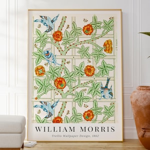 May include: A framed print of William Morris's Trellis Wallpaper Design from 1862. The artwork features a grid pattern with green leaves, orange flowers, and blue birds. The print is in a gold frame and is displayed indoors.
