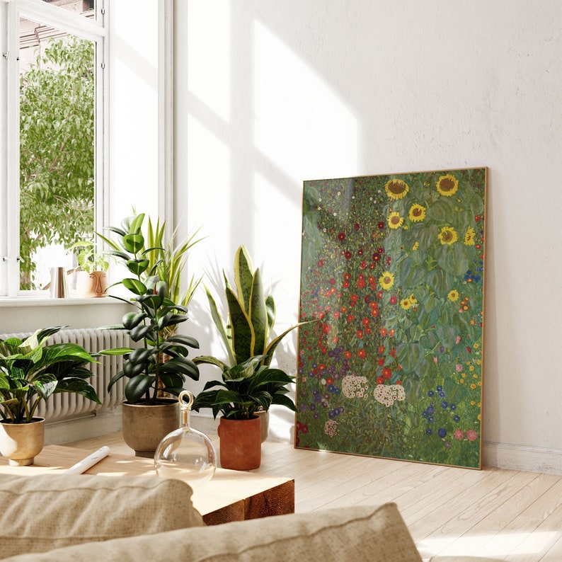 May include: A framed print of a colorful floral painting with sunflowers, red flowers, and green foliage. The print is hanging on a white wall in a room with houseplants and a wooden coffee table.