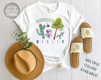 May include: White t-shirt with a graphic of a cactus, tree, and flowers. The text "DIVERSITY is BEAUTY" is written in rainbow colors.