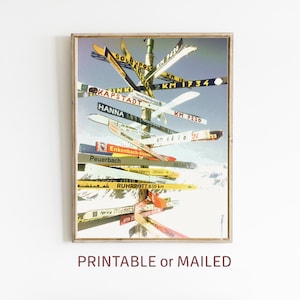 May include: A vintage ski signpost with multiple wooden skis pointing in different directions. The skis are painted with various colors and have destinations and distances written on them. The signpost is set against a snowy mountain backdrop.