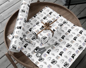 Puede incluir: Papel de regalo blanco con un patrón repetitivo de siluetas negras de parejas de novios, pasteles de boda y anillos, junto con una caja de regalo envuelta, una cinta marrón y unas tijeras grises sobre la superficie.