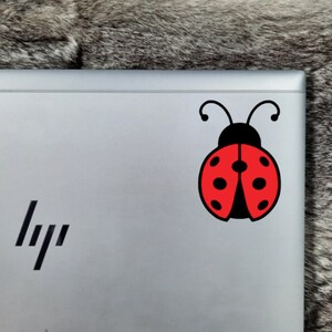Lady Bug Decal with Red Wings and A Black Body on the Top Right Hand Corner of an HP Laptop