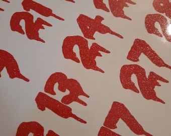 May include: A sheet of adhesive decals featuring numbers printed in a red, glittery, dripping font style. The numbers visible include 12, 13, 17, 21, 24, 25, 27, and 28, all rendered with a distinct melting or liquid effect on a plain white background.