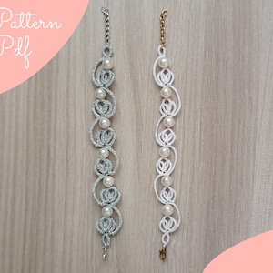 Könnte beinhalten: Zwei Armbänder mit einem zarten, komplizierten Design. Ein Armband ist silber mit weißen Perlen, das andere ist weiß mit weißen Perlen.