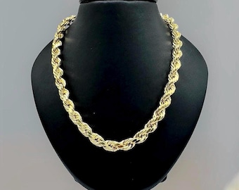May include: A gold rope chain necklace on a black display stand.