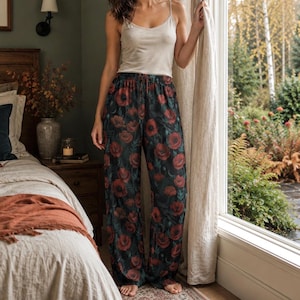May include: A beige spaghetti strap tank top paired with loose-fitting, dark-colored pajama pants featuring a vibrant red poppy flower print. The pants have a drawstring waist and a wide-leg silhouette, creating a comfortable loungewear set.