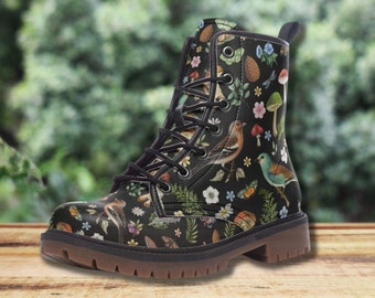 May include: Black combat boot featuring a nature-themed pattern with birds, mushrooms, flowers, and foliage. The boot has a lace-up design, a brown sole, and a pull tab at the back. The boot is approximately 6 inches tall.