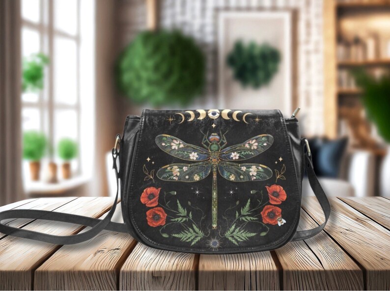 May include: Black leather crossbody bag with a dragonfly design, red poppies, and gold accents. The bag has a long adjustable strap.