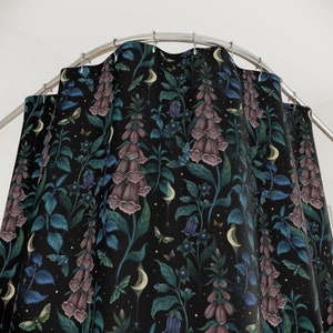 May include: A black shower curtain with a repeating pattern of purple foxglove flowers, green leaves, and white crescent moons. The background is a dark navy blue.