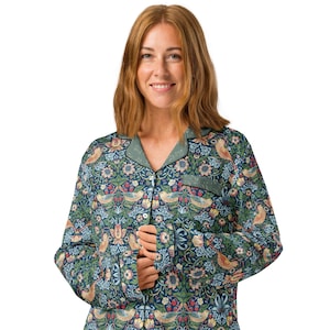 May include: A long-sleeved pajama top with a floral and bird pattern in shades of blue, green, and peach. The pajama top has a collared neckline with green trim and button closures. The fabric features a detailed botanical design.