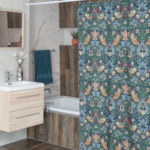 Puede incluir: Una cortina de ducha azul con un patr&oacute;n floral que presenta p&aacute;jaros y hojas. La cortina tiene una barra blanca y est&aacute; colgada en un ba&ntilde;o con una ba&ntilde;era blanca y azulejos de imitaci&oacute;n de madera.