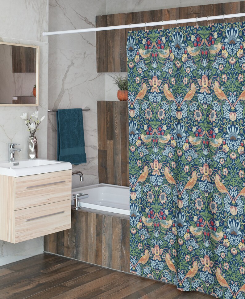 Puede incluir: Una cortina de ducha azul con un patr&oacute;n floral que presenta p&aacute;jaros y hojas. La cortina tiene una barra blanca y est&aacute; colgada en un ba&ntilde;o con una ba&ntilde;era blanca y azulejos de imitaci&oacute;n de madera.