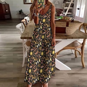 May include: A black maxi dress with a floral print featuring butterflies, moons and suns. The dress has a V-neckline and spaghetti straps.