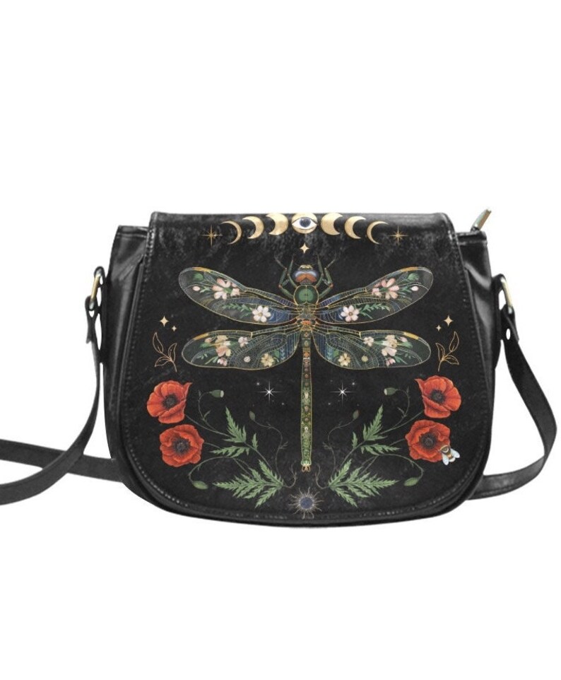 May include: Black leather crossbody bag with a dragonfly design. The dragonfly is surrounded by flowers and stars. The bag has a gold chain strap.
