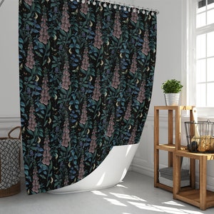 May include: A black shower curtain with a floral pattern featuring pink and blue flowers on a dark background. The flowers are stylized and resemble foxgloves. The curtain is hanging in a bathroom with a white bathtub and a wooden shelf unit.