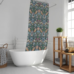 Puede incluir: Una cortina de ducha azul y verde con un patr&oacute;n floral y de p&aacute;jaros. La cortina est&aacute; colgada en un ba&ntilde;o con una ba&ntilde;era blanca y una estanter&iacute;a de madera.