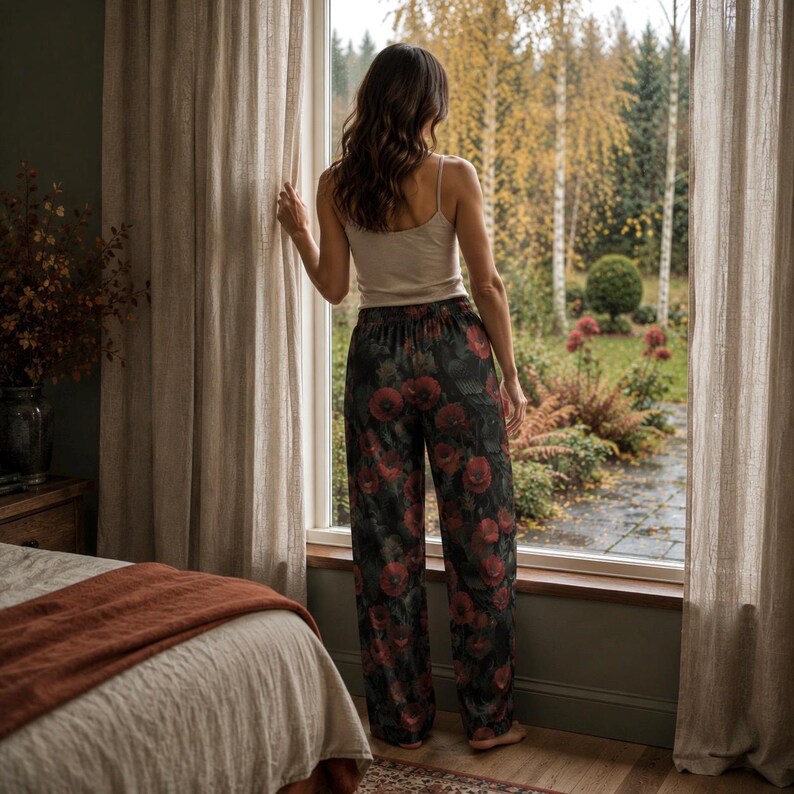 May include: A beige camisole top paired with loose-fitting trousers featuring a dark background and a vibrant red floral print. The trousers have a high-waisted elastic band design and a straight-leg cut that falls to the floor in a relaxed fit.