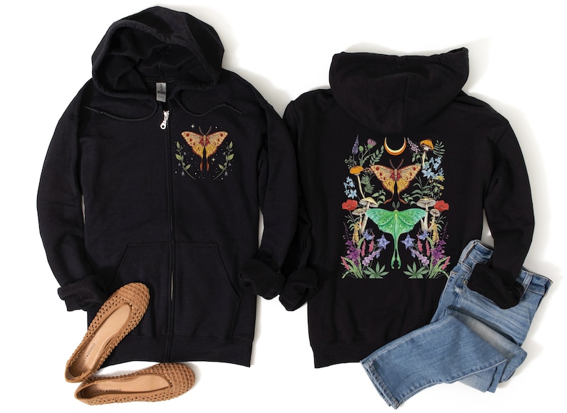 May include: Two black zip-up hoodies with a moth and floral design. The hoodie on the left has a single moth on the front, while the hoodie on the right has a larger design with two moths and flowers on the back.