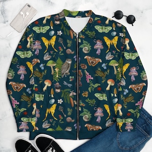 May include: A dark blue bomber jacket with a full-color print of various forest creatures, including owls, butterflies, mushrooms, snails, and leaves. The print is repeated throughout the jacket.