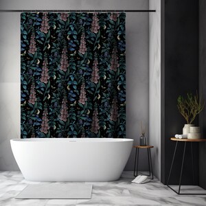 May include: A black shower curtain with a floral pattern featuring pink and blue flowers on a dark background. The curtain is hanging in a bathroom with a white bathtub and a black side table.