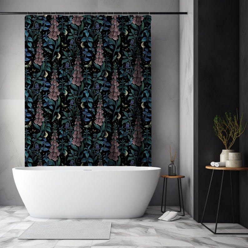 May include: A black shower curtain with a floral pattern featuring pink and blue flowers on a dark background. The curtain is hanging in a bathroom with a white bathtub and a black side table.