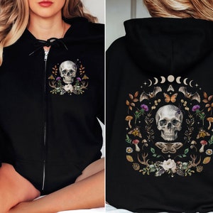 May include: Black zip-up hoodie with a skull and floral design on the front and a skull surrounded by moons, bats, and flowers on the back.